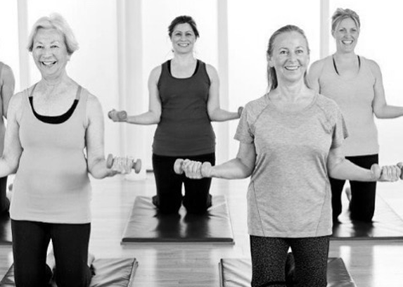 Middle aged women using hand weights in a Pilates class